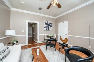 Living area featuring visible vents, crown molding