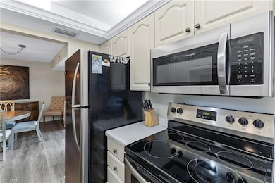 Kitchen featuring appliances with stainless steel finishes, light wood-type flooring, light countertops, and a chandelier