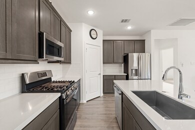 You will love the details of this kitchen! It's finished with a largle single basin sink, quartz countertops, a walk-in pantry, and sleek white tile backsplash. There is plenty of storage and counterspace making this kitchen every chef's dream!