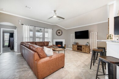 Family room boasts tile flooring, ceiling fan, crown molding and a corner gas log fireplace with Dekton surround.
