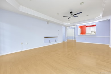 Living Room with a tray ceiling, ornamental molding, wood finished floors, a ceiling fan, and recessed lighting