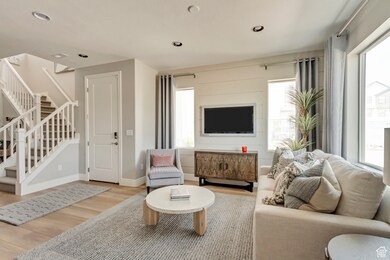 PHOTOS FOM SIMILAR MODEL HOME. FINISHES, COLORS, AND OPTIONS WILL VARY. Living area with plenty of natural light, stairway, wood finished floors, and recessed lighting