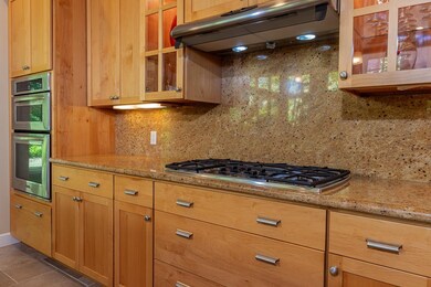Specimen granite countertops and a full-height backsplash adds texture and sophistication