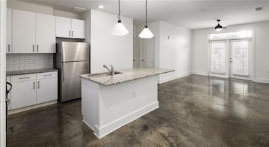 Kitchen featuring stainless steel refrigerator, ceiling fan, tasteful backsplash, sink, and pendant lighting