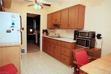 Kitchen featuring ceiling fan, white fridge, sink, and light tile floors