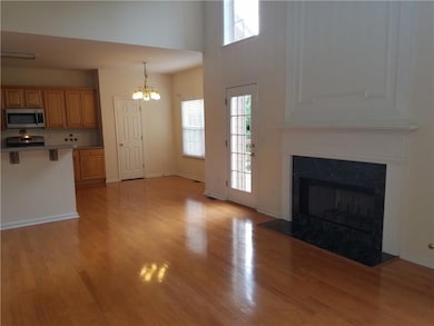 Unfurnished living room with healthy amount of natural light, light wood-style floors, a high end fireplace, a chandelier, and a towering ceiling