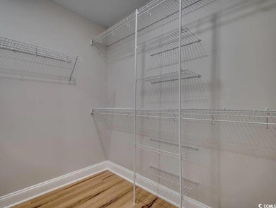 Spacious closet featuring wood finished floors and attic access