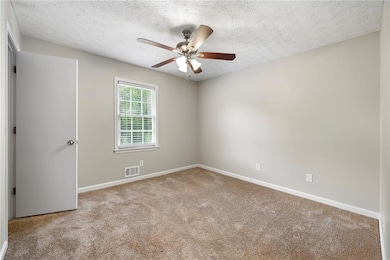 Carpeted spare room featuring a textured ceiling and ceiling fan
