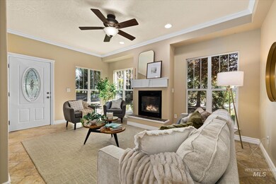 Living area featuring plenty of natural light, crown molding, a glass covered fireplace, a ceiling fan, and a textured ceiling