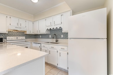 Kitchen with white appliances, light tile patterne