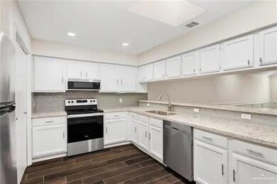 Kitchen with appliances with stainless steel finishes, a sink, white cabinetry, dark wood-style floors, and recessed lighting