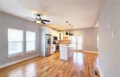 Kitchen with sink, white cabinetry, hanging light fixtures, stainless steel appliances, and a center island