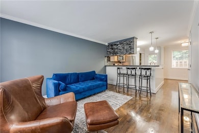 Living area with ornamental molding, wood finished floors, and baseboards