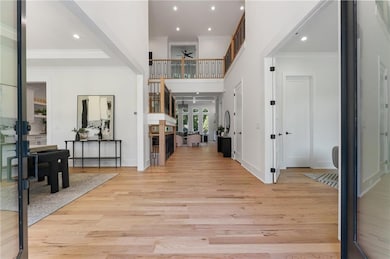 Foyer entrance with crown molding, light wood-style floors, recessed lighting, a ceiling fan, and a high ceiling