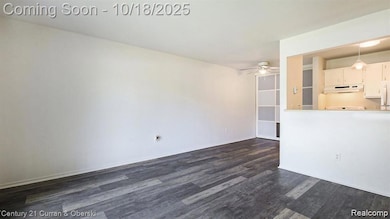 Unfurnished living room featuring dark wood-type flooring and a ceiling fan