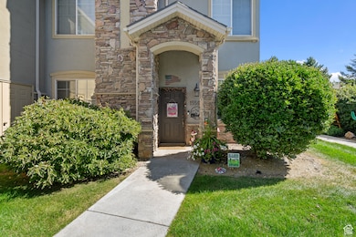 Entrance to property featuring stone siding, a lawn, and stucco siding