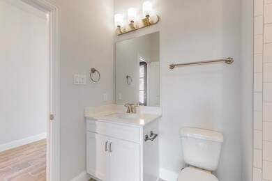 Full bath with toilet, baseboards, wood finished f