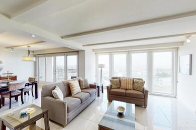 Living room with rail lighting, beam ceiling, and light tile floors