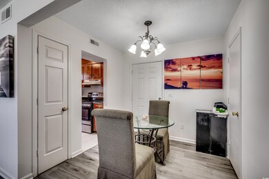 Dining room with light wood-style flooring, a chandelier, a textured ceiling, and baseboards