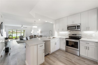 Kitchen featuring stainless steel appliances, open floor plan, a peninsula, a sink, and backsplash