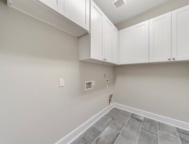 Spacious laundry with extra cabinets for storage, and plenty of room for a second refrigerator.