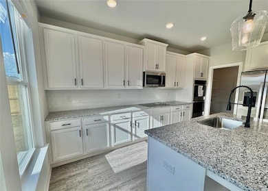 Kitchen with white cabinetry, light stone countert