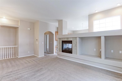 Living room with entertainment center and 2-sided fireplace. Nice and bright.  Living room has a black out window blind.  The archway leads to the primary bedroom.
