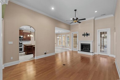 Unfurnished living room with a wealth of natural light, ceiling fan with notable chandelier, and light wood finished floors