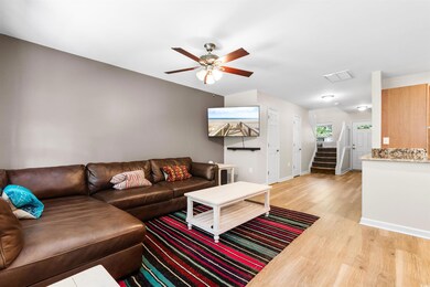 Living room with ceiling fan and light wood-type f