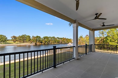Balcony featuring a water view, view of wooded area, and a ceiling fan