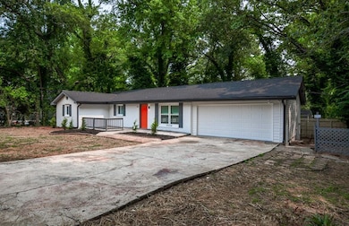 Single story home with an attached garage, driveway, covered porch, and brick siding