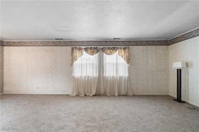 Unfurnished living room with wallpapered walls and light carpet