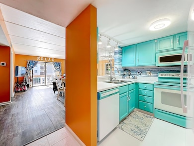Kitchen with white appliances, light countertops, rail lighting, tasteful backsplash, and light tile patterned floors