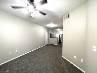 Spare room featuring ceiling fan, dark carpet, and
