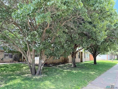 View of property hidden behind natural elements with brick siding and a front yard