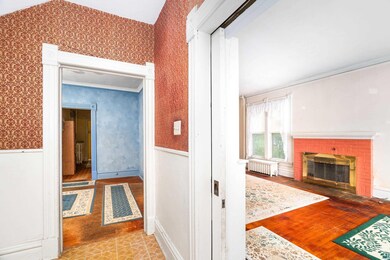 Corridor with radiator, wallpapered walls, wainscoting, and wood finished floors