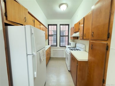 Kitchen featuring white appliances, light countertops, brown cabinets, and under cabinet range hood