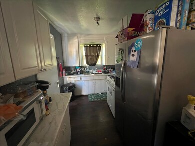 Kitchen with a textured ceiling, white cabinetry, 