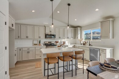 Kitchen with lofted ceiling, a kitchen bar, decorative light fixtures, a kitchen island, and stainless steel appliances