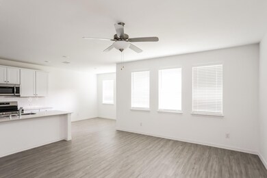 Kitchen with ceiling fan, sink, backsplash, white cabinetry, and light wood-type flooring