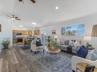 Living area with lofted ceiling, dark wood-type flooring, a ceiling fan, and french doors