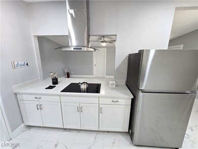 Kitchen with marble finish floor, white cabinetry,