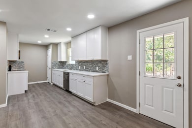 Kitchen with white cabinetry, backsplash, light w