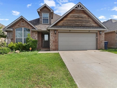 View of front facade featuring concrete driveway, a garage, a front yard, roof with shingles, and brick siding