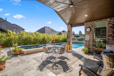 This inviting backyard features a massive, covered patio that overlooks a sparkling pool surrounded by lush greenery, offering a private and serene retreat.