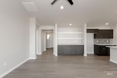 Kitchen with tasteful backsplash, dark brown cabinetry, light wood-style floors, recessed lighting, and open floor plan