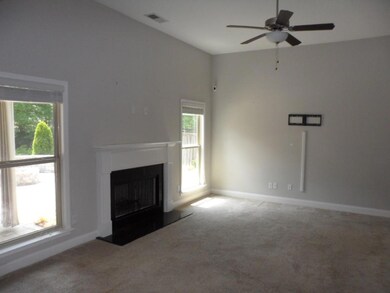 Unfurnished living room with carpet, healthy amount of natural light, a fireplace with raised hearth, a ceiling fan, and lofted ceiling
