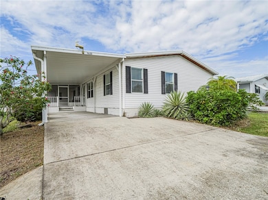 View of front of property featuring driveway, a carport, and covered porch