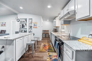Kitchen featuring white cabinetry, dark hardwood /