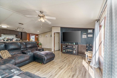 Living room featuring wood finished floors, lofted ceiling, and ceiling fan